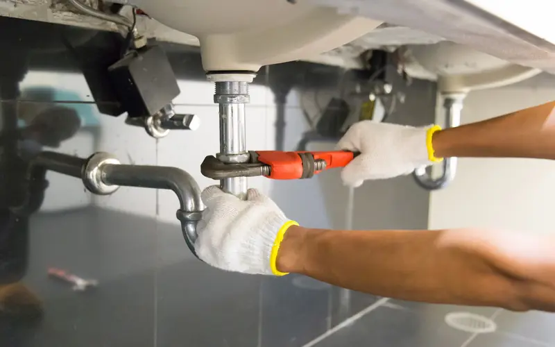Plumber fixing a pipe under a sink